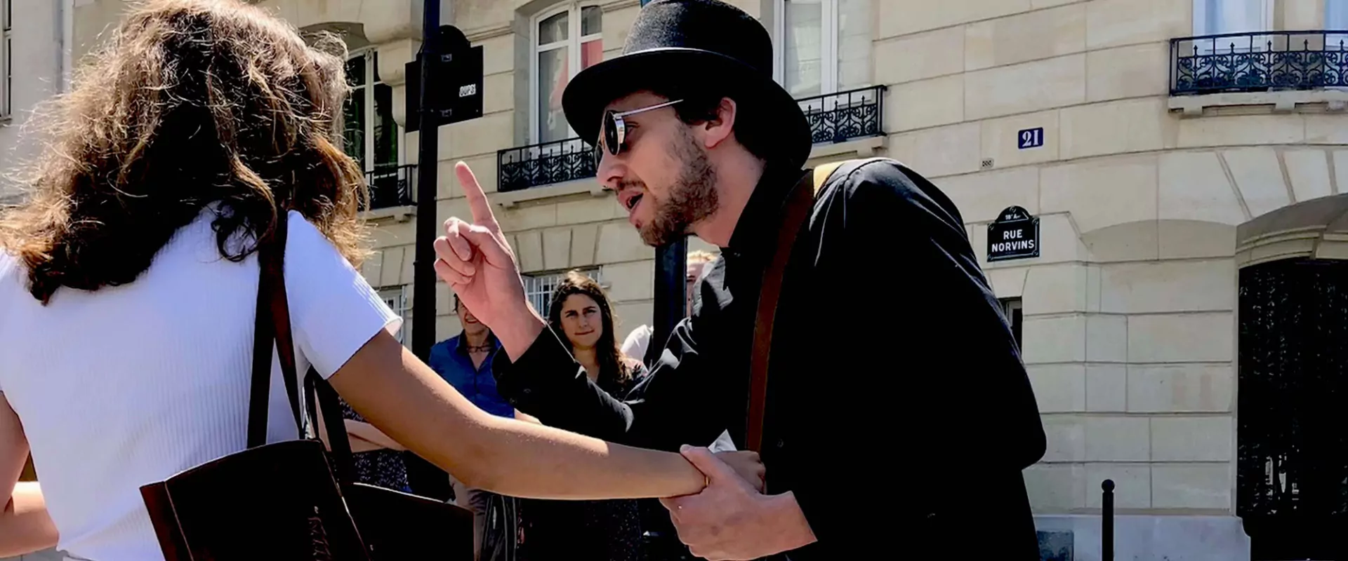 Un comédien en chapeau haut-de-forme interpelle une joueuse dans la rue