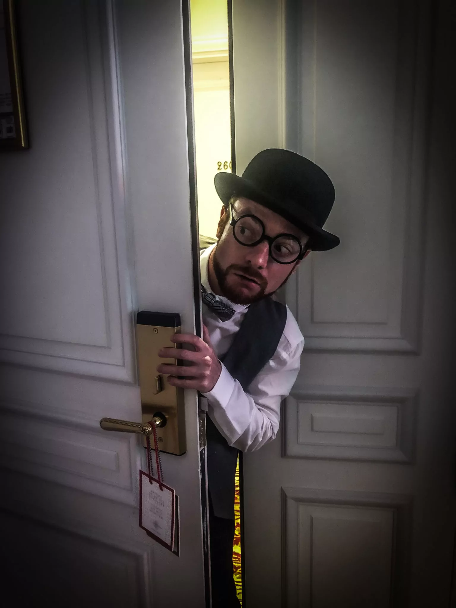 Un comédien en chapeau melon passe la tête par la porte