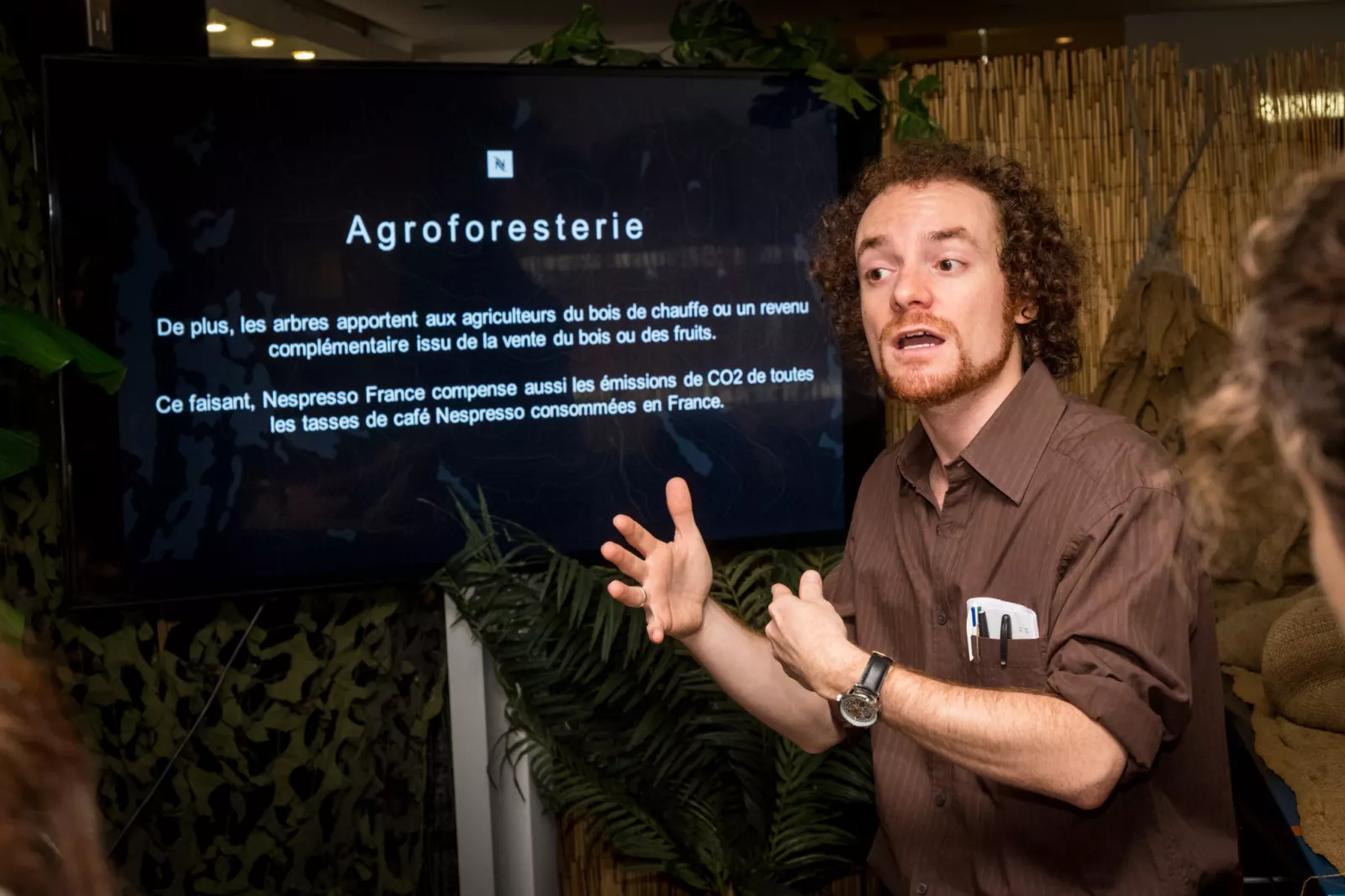 Le comédien explique une énigme devant l'écran du jeu