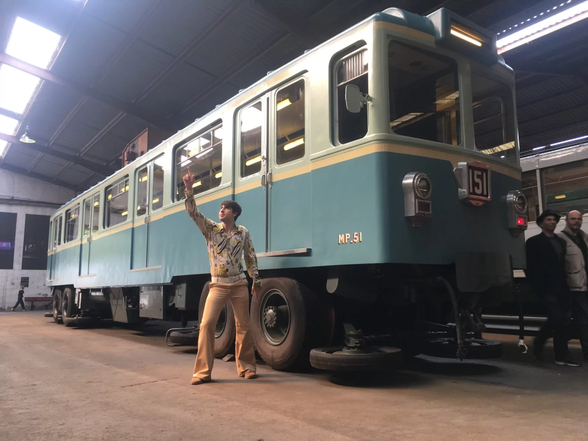Un comédien bras levé devant une rame de métro historique