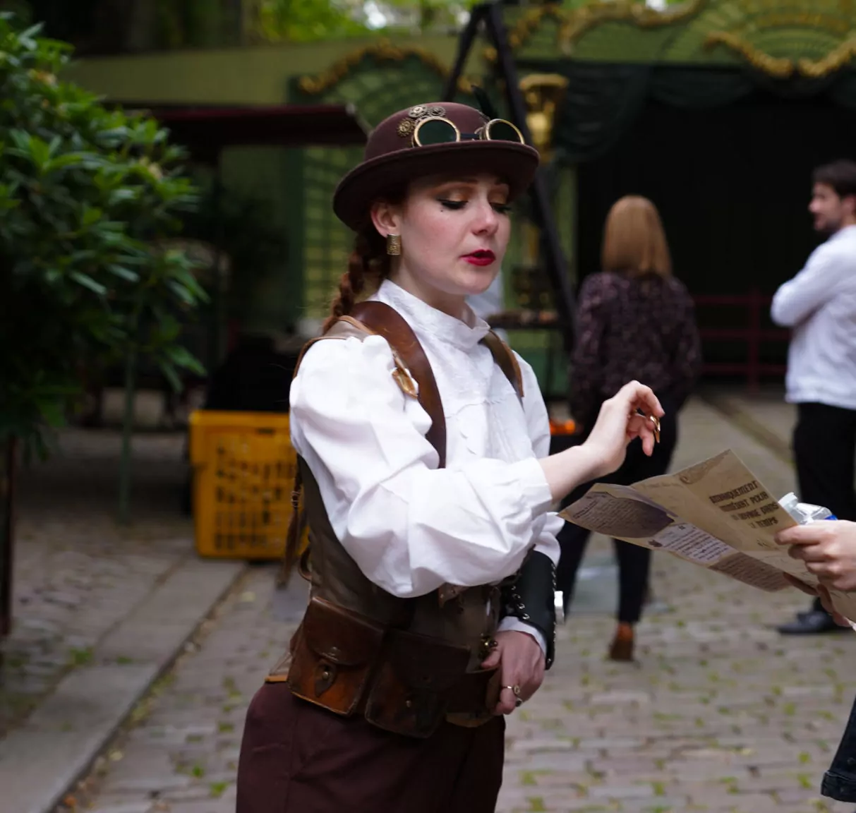 Une comédienne en tenue steampunk tend un document